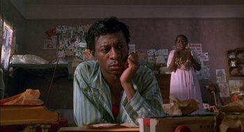 Movie still from “The Five Heartbeats” (1991), directed by Robert Townsend – A man sitting at a table in a room; Medium shot, Low angle