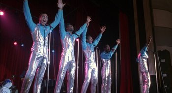 Movie still from “The Five Heartbeats” (1991), directed by Robert Townsend – A group of men standing next to each other on a stage; Medium shot, Low angle