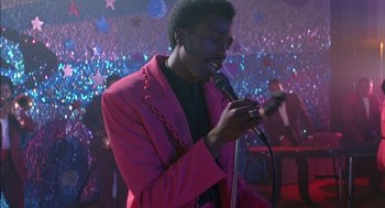 Movie still from “The Five Heartbeats” (1991), directed by Robert Townsend – A man in a pink jacket holding a microphone; Medium shot, Over the shoulder angle