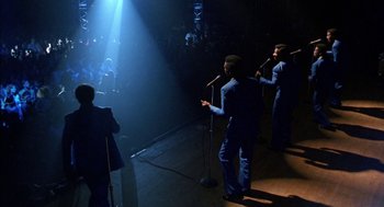 Movie still from “The Five Heartbeats” (1991), directed by Robert Townsend – A group of men standing next to each other on a stage with microphones; Extreme Wide shot, High angle
