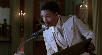 Movie still from “The Five Heartbeats” (1991), directed by Robert Townsend – A man in a white suit is talking on a microphone; Close Up shot, Low angle