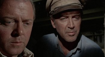 Movie still from “The Flight of the Phoenix” (1965), directed by Robert Aldrich – A man wearing a hat and a jacket; Close Up shot, Over the shoulder angle