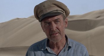 Movie still from “The Flight of the Phoenix” (1965), directed by Robert Aldrich – An older man wearing a hat in the desert; Close Up shot, Low angle