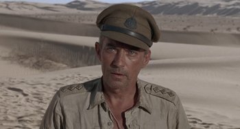 Movie still from “The Flight of the Phoenix” (1965), directed by Robert Aldrich – A person wearing a hat on a beach; Close Up shot, Low angle