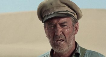 Movie still from “The Flight of the Phoenix” (1965), directed by Robert Aldrich – An older man wearing a hat and a green shirt; Close Up shot, Low angle