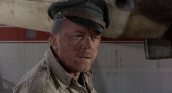 Movie still from “The Flight of the Phoenix” (1965), directed by Robert Aldrich – An older man wearing a hat and a jacket; Close Up shot, Over the shoulder angle