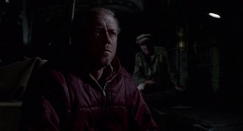 Movie still from “The Flight of the Phoenix” (1965), directed by Robert Aldrich – A man wearing a red jacket in a dark room; Medium shot, Over the shoulder angle