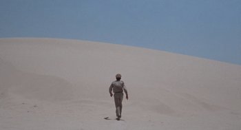Movie still from “The Flight of the Phoenix” (1965), directed by Robert Aldrich – A man walking on top of a sand dune; Extreme Wide shot, Low angle