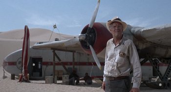 Movie still from “The Flight of the Phoenix” (1965), directed by Robert Aldrich – An older man standing in front of an airplane; Wide shot, Low angle
