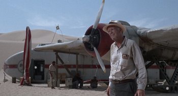 Movie still from “The Flight of the Phoenix” (1965), directed by Robert Aldrich – A man standing in front of an airplane on the beach; Wide shot, Low angle