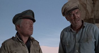 Movie still from “The Flight of the Phoenix” (1965), directed by Robert Aldrich – Two men wearing hats and standing next to each other; Close Up shot, Low angle