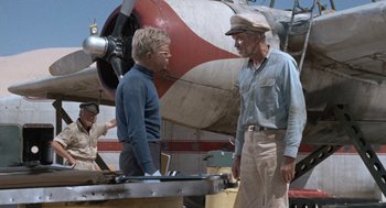Movie still from “The Flight of the Phoenix” (1965), directed by Robert Aldrich – Two men standing in front of an old airplane; Medium shot, Low angle