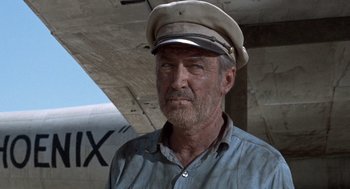 Movie still from “The Flight of the Phoenix” (1965), directed by Robert Aldrich – An older man wearing a hat and a blue shirt; Close Up shot, Low angle