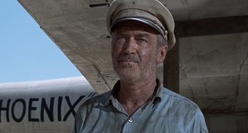 Movie still from “The Flight of the Phoenix” (1965), directed by Robert Aldrich – An older man wearing a hat and a blue shirt; Close Up shot, Low angle