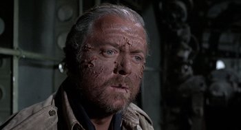 Movie still from “The Flight of the Phoenix” (1965), directed by Robert Aldrich – An old man with a beard and a lot of dirt on his face; Close Up shot, Over the shoulder angle