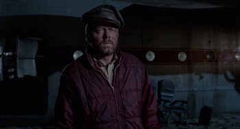 Movie still from “The Flight of the Phoenix” (1965), directed by Robert Aldrich – A man wearing a hat and a red jacket; Medium shot, High angle