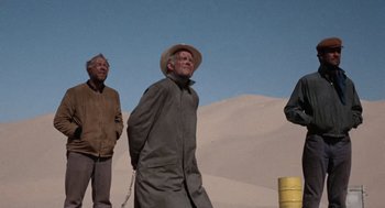 Movie still from “The Flight of the Phoenix” (1965), directed by Robert Aldrich – A group of men standing next to each other on top of a hill; Wide shot, Low angle
