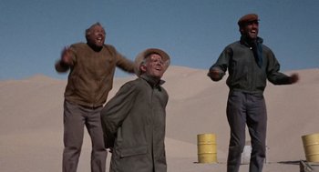 Movie still from “The Flight of the Phoenix” (1965), directed by Robert Aldrich – A group of men standing on top of a sand dune; Wide shot, Low angle