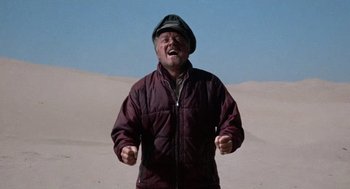 Movie still from “The Flight of the Phoenix” (1965), directed by Robert Aldrich – A man standing in the sand with his mouth wide open; Medium shot, Low angle