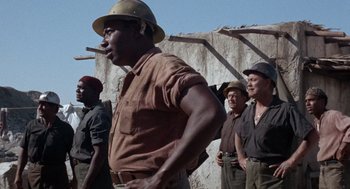 Movie still from “The Flight of the Phoenix” (1965), directed by Robert Aldrich – A group of men standing next to each other; Medium shot, Low angle