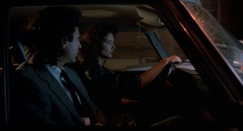 Movie still from “The Fly” (1986), directed by David Cronenberg – A man and a woman sitting in the drivers seat of a car at night; Medium shot, Over the shoulder angle