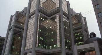 Movie still from “The Fly” (1986), directed by David Cronenberg – A large building with many windows and lights; Extreme Wide shot, Low angle