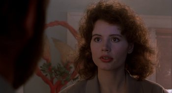 Movie still from “The Fly” (1986), directed by David Cronenberg – A person with curly hair looking at the camera; Close Up shot, Over the shoulder angle