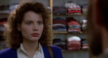 Movie still from “The Fly” (1986), directed by David Cronenberg – A young woman standing in front of shelves of clothes; Close Up shot, Over the shoulder angle