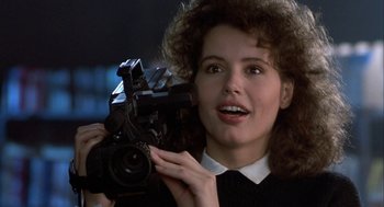 Movie still from “The Fly” (1986), directed by David Cronenberg – A woman is holding a video camera up to her face; Close Up shot, Low angle