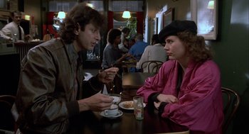 Movie still from “The Fly” (1986), directed by David Cronenberg – A man and a woman sitting at a table in a restaurant; Medium shot, Over the shoulder angle