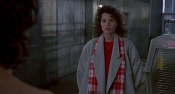 Movie still from “The Fly” (1986), directed by David Cronenberg – A woman wearing a red shirt and a gray jacket; Medium shot, Over the shoulder angle