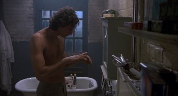 Movie still from “The Fly” (1986), directed by David Cronenberg – A shirtless man in a bathroom washing his hands; Medium shot, Low angle