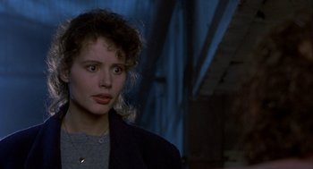 Movie still from “The Fly” (1986), directed by David Cronenberg – A young woman in a black jacket looking to her left; Close Up shot, Over the shoulder angle