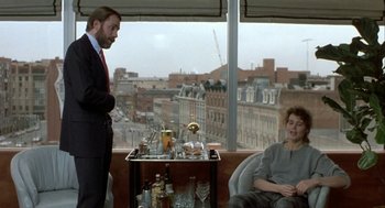 Movie still from “The Fly” (1986), directed by David Cronenberg – A man and a woman sitting in front of a window; Medium shot, Over the shoulder angle