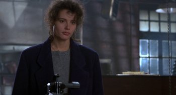 Movie still from “The Fly” (1986), directed by David Cronenberg – A woman in a black jacket standing next to a camera; Close Up shot, Over the shoulder angle