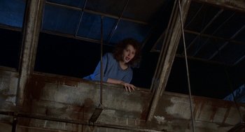 Movie still from “The Fly” (1986), directed by David Cronenberg – A young woman standing on top of a wooden structure; Medium shot, Low angle