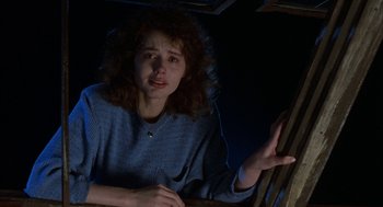 Movie still from “The Fly” (1986), directed by David Cronenberg – A young woman in a blue shirt is looking at the camera; Close Up shot, Low angle