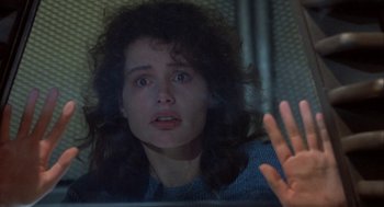 Movie still from “The Fly” (1986), directed by David Cronenberg – A woman looking at the camera through a window; Close Up shot, Over the shoulder angle