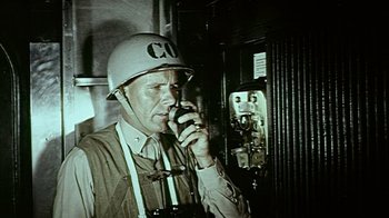 Movie still from “The Fog of War” (2003), directed by Errol Morris – A man wearing a helmet talking on a cell phone; Close Up shot, Low angle