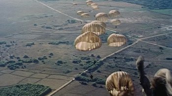 Movie still from “The Fog of War” (2003), directed by Errol Morris – A group of parachutists flying over a field; Extreme Wide shot, High angle