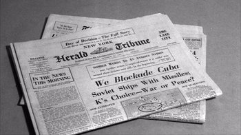 Movie still from “The Fog of War” (2003), directed by Errol Morris – Two newspapers are laying side by side on a table; Extreme Close Up shot, High angle
