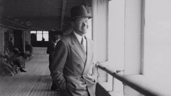 Movie still from “The Fog of War” (2003), directed by Errol Morris – An old photo of a man in a suit and a hat; Medium shot, High angle