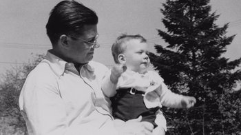 Movie still from “The Fog of War” (2003), directed by Errol Morris – An old photo of a man holding a baby; Medium shot, High angle