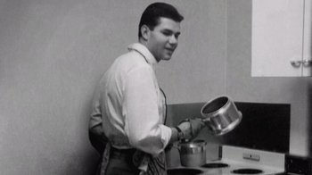 Movie still from “The Fog of War” (2003), directed by Errol Morris – A black and white photo of a man cooking in a kitchen; Medium shot, Low angle