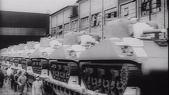 Movie still from “The Fog of War” (2003), directed by Errol Morris – A black and white photo of tanks parked in a warehouse; Wide shot, Low angle