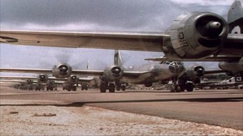 Movie still from “The Fog of War” (2003), directed by Errol Morris – A group of planes sitting on top of an airport runway; Wide shot, Low angle