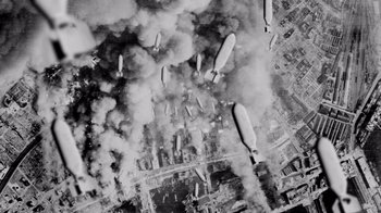 Movie still from “The Fog of War” (2003), directed by Errol Morris – An aerial view of a city with a bunch of airplanes flying over it; Extreme Wide shot, Overhead angle