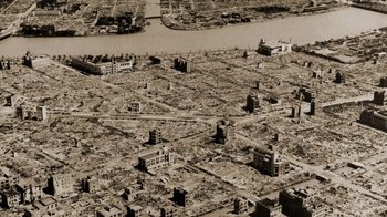 Movie still from “The Fog of War” (2003), directed by Errol Morris – An aerial view of a destroyed city with a river in the background; Extreme Wide shot, High angle
