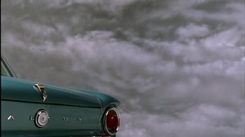 Movie still from “The Fog of War” (2003), directed by Errol Morris – The tail light of an old car under a cloudy sky; Wide shot, Low angle