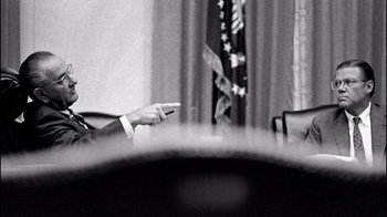Movie still from “The Fog of War” (2003), directed by Errol Morris – A man in a white shirt is sitting at a table; Medium shot, Over the shoulder angle